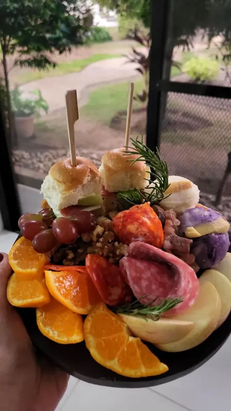 Assortiment de fruits, de charcuterie et de fromages présentés sur un plateau.