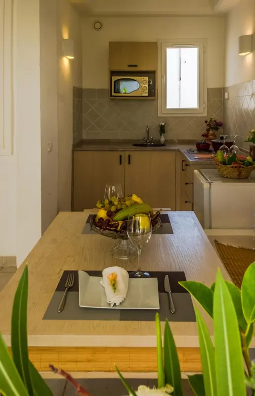 Une table est dressée avec des fruits et de la vaisselle dans une cuisine.