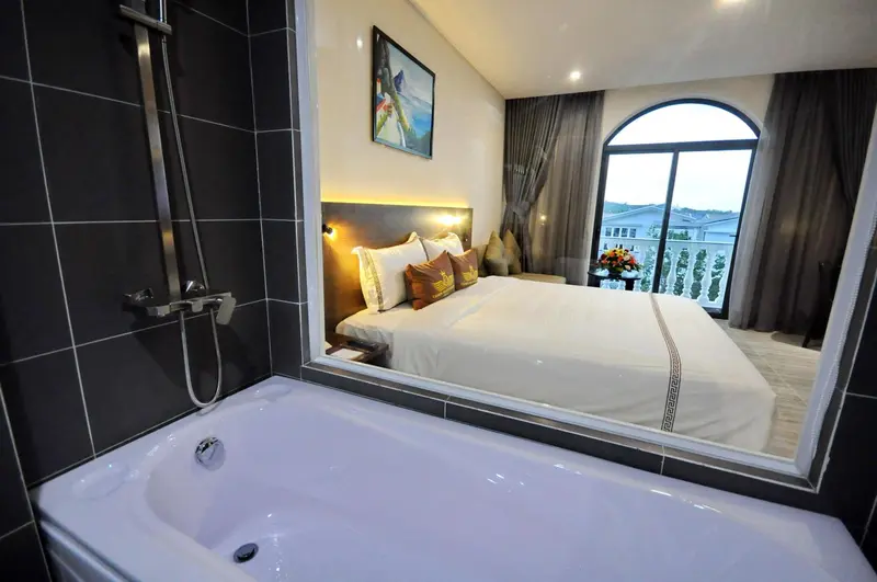 Une chambre lumineuse avec un grand lit et une baignoire.