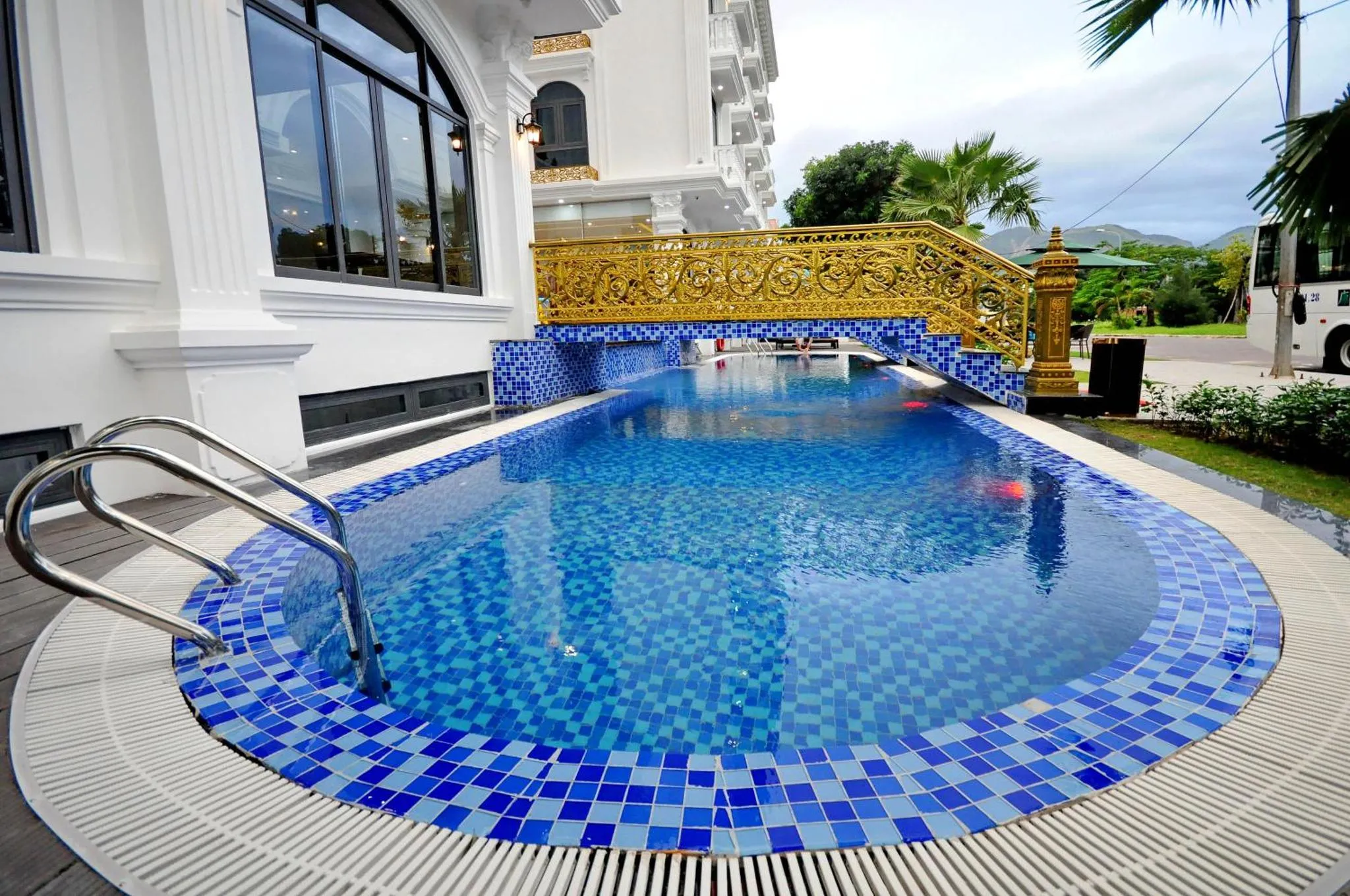 Une piscine rectangulaire bleue entourée d'une terrasse carrelée.