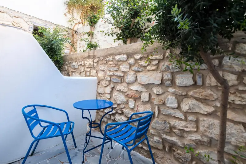 Petite table bleue et chaises en fer forgé sur une terrasse en pierre.