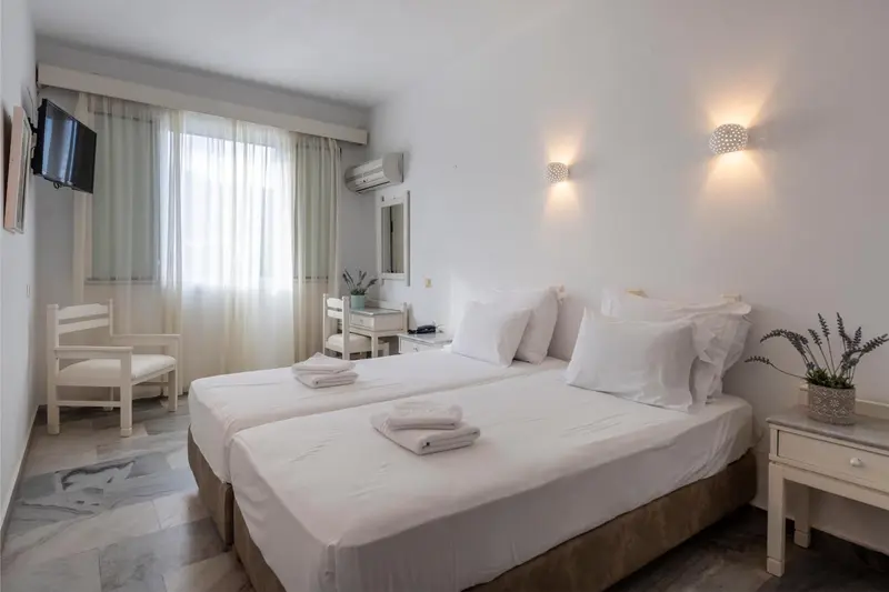 Une chambre lumineuse avec deux lits simples et une décoration sobre.