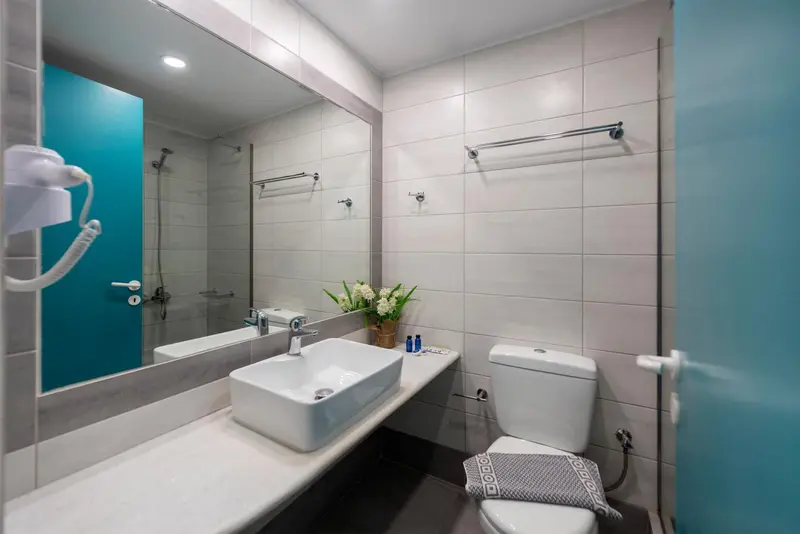 Une salle de bain moderne avec carrelage gris et un grand miroir.