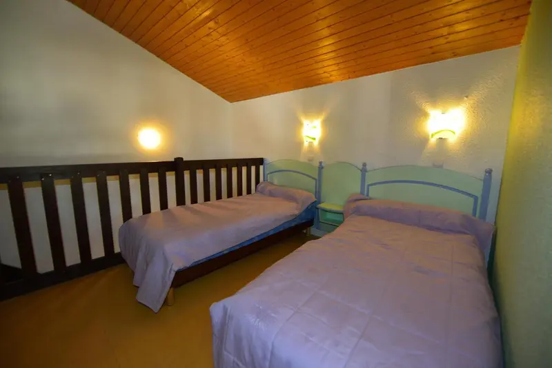 Une chambre avec deux lits simples et des murs colorés.