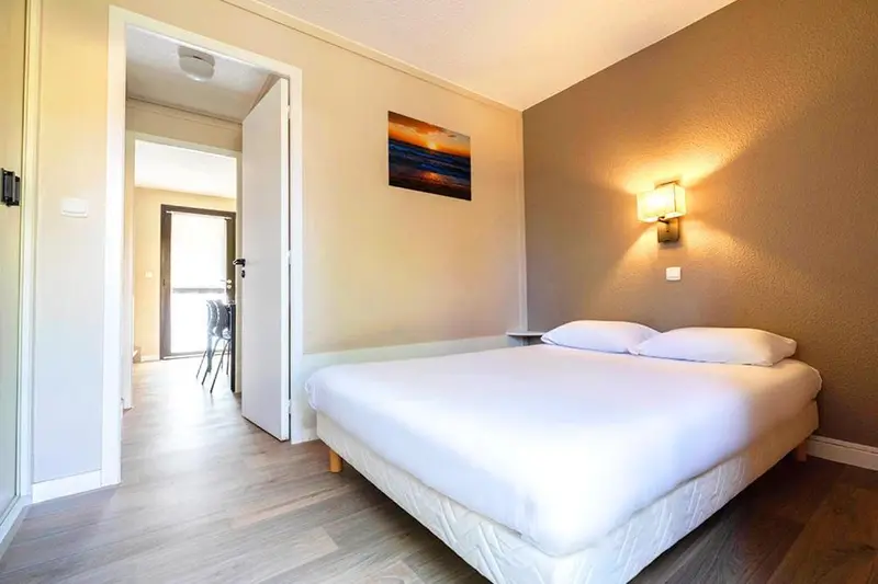 Une chambre lumineuse avec un lit double et un accès à un espace repas.
