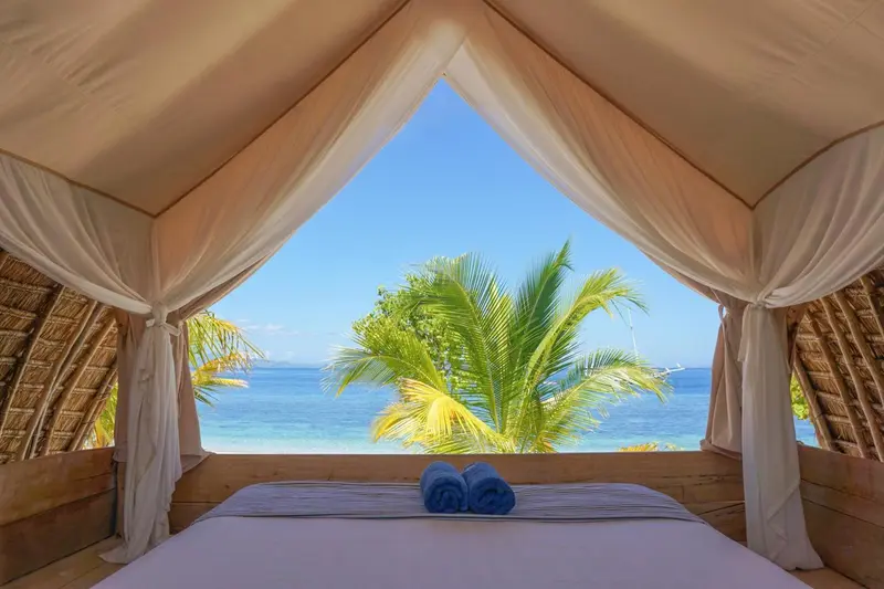 Un lit est dispose dans une structure ouverte sur une vue mer et vegetale.