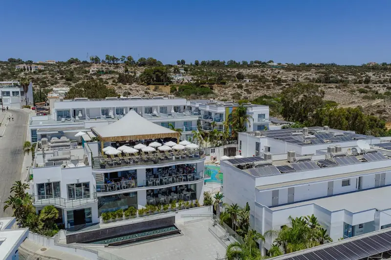 Vue aérienne d'un complexe hôtelier blanc avec piscine et végétation.