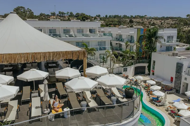 Terrasse ombragée avec mobilier de détente et piscine en contrebas.
