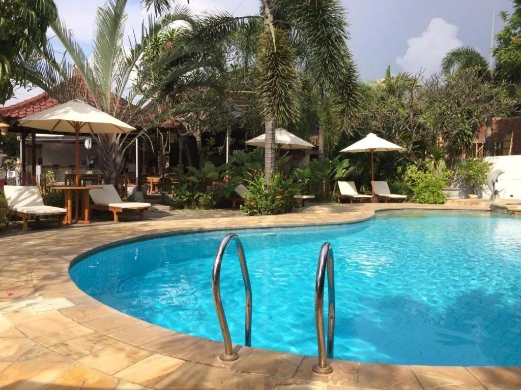 Une piscine rectangulaire bordée d'une terrasse avec des transats et des parasols.