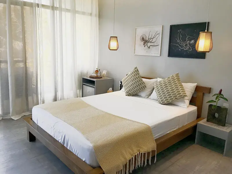 Une chambre lumineuse avec un lit recouvert d'une couverture texturée et des coussins.