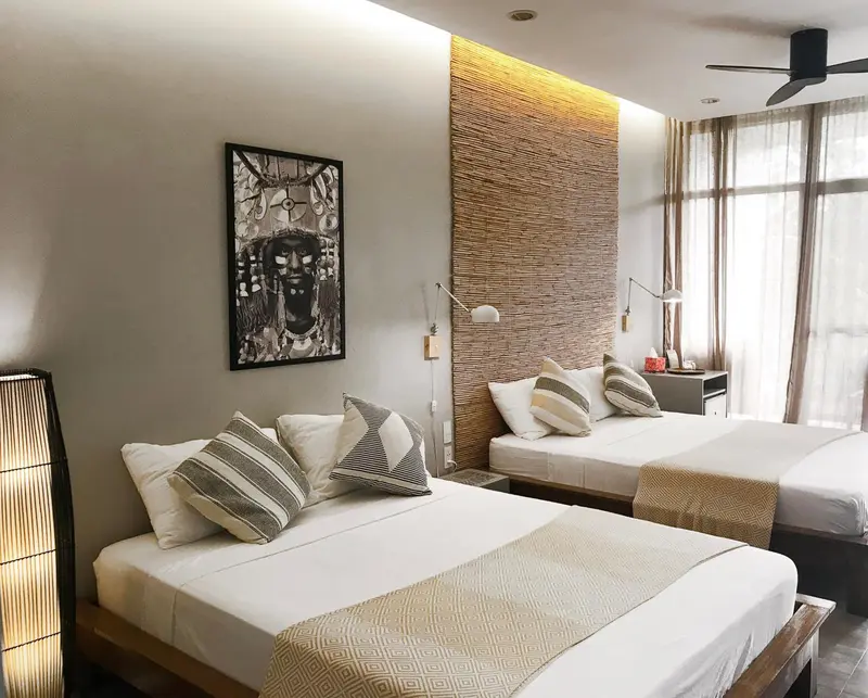 Une chambre lumineuse avec deux lits simples et une décoration murale en fibres naturelles.
