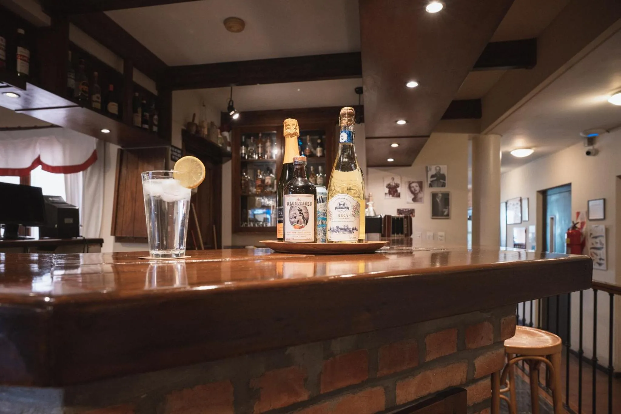 Un comptoir de bar en bois présente des bouteilles et un verre décoré d'une tranche de citron.