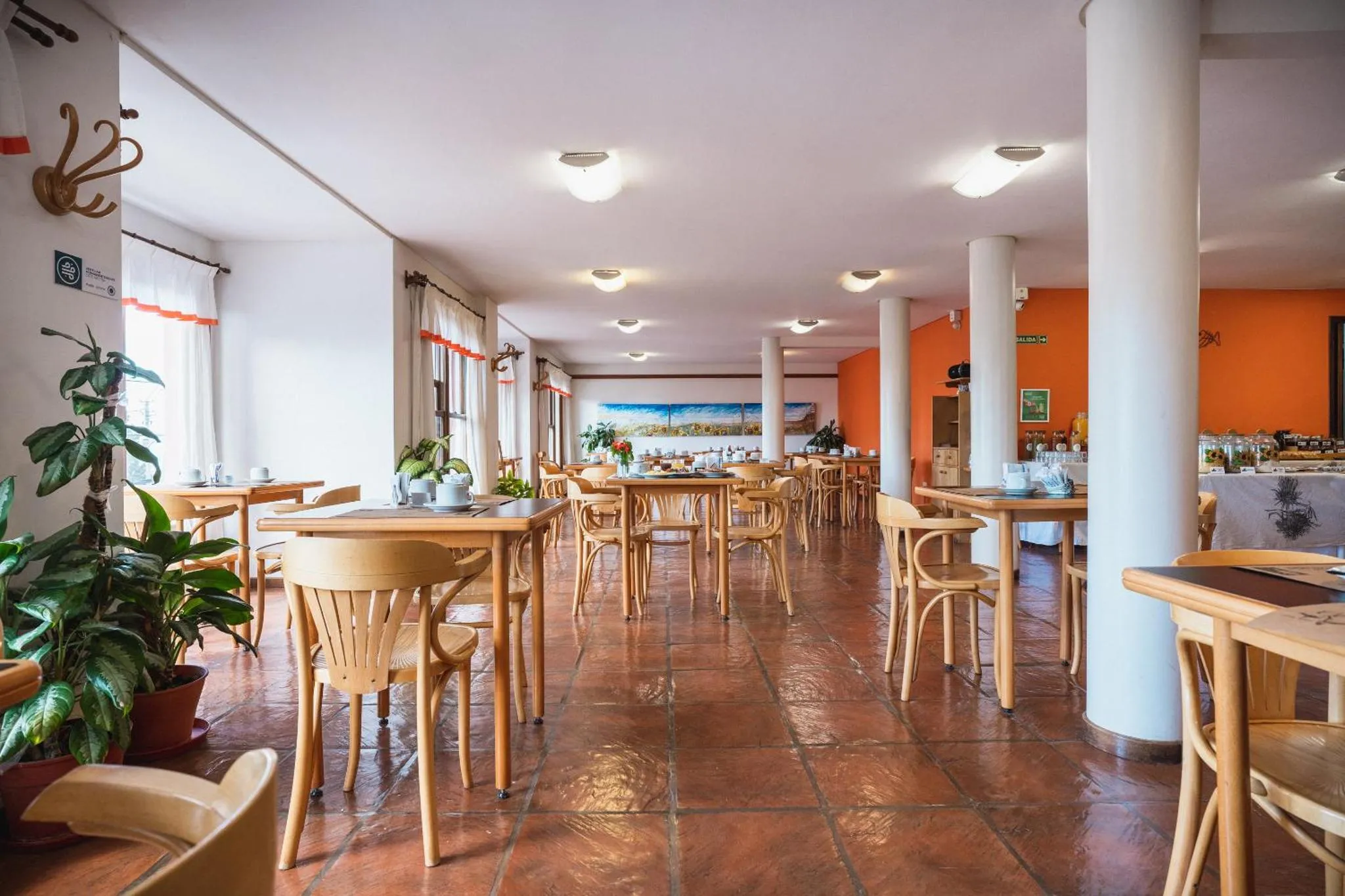 Une salle lumineuse avec des tables et des chaises disposées pour les repas.