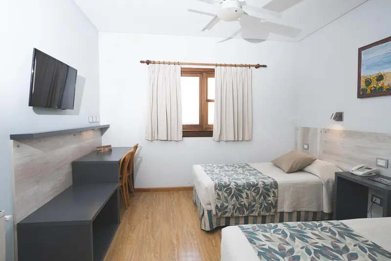 Une chambre lumineuse avec deux lits simples et un bureau.