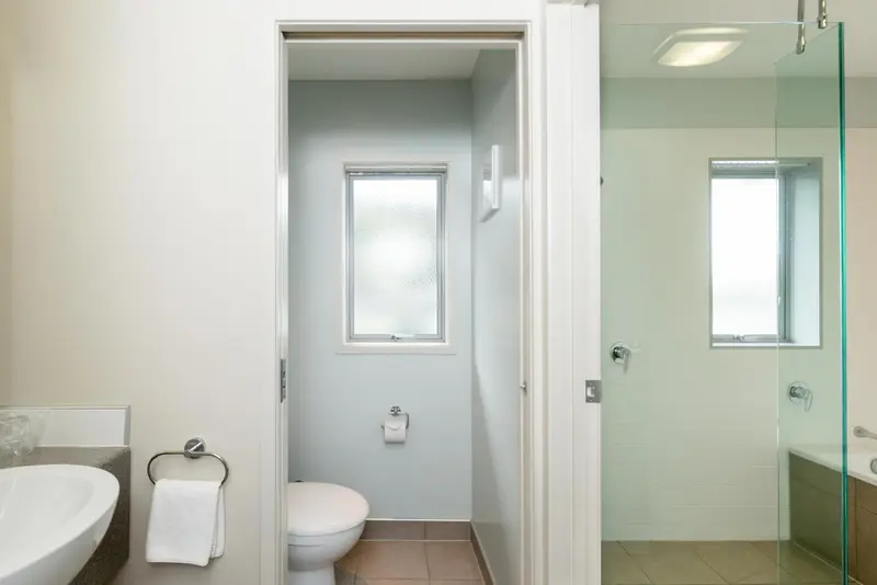 Une salle de bain claire avec douche à l'italienne et toilette.