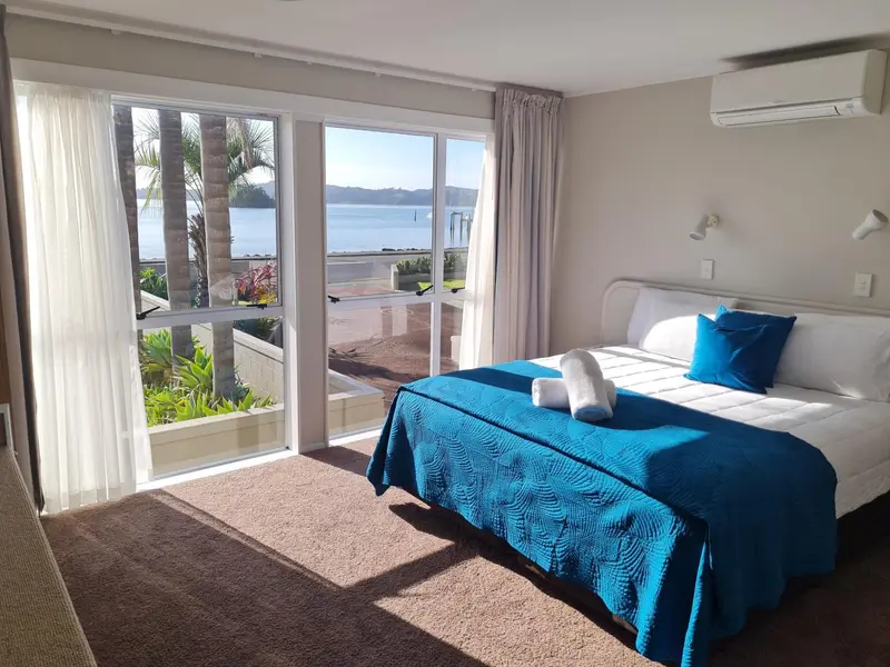 Une chambre lumineuse avec un grand lit donnant sur une vue mer.