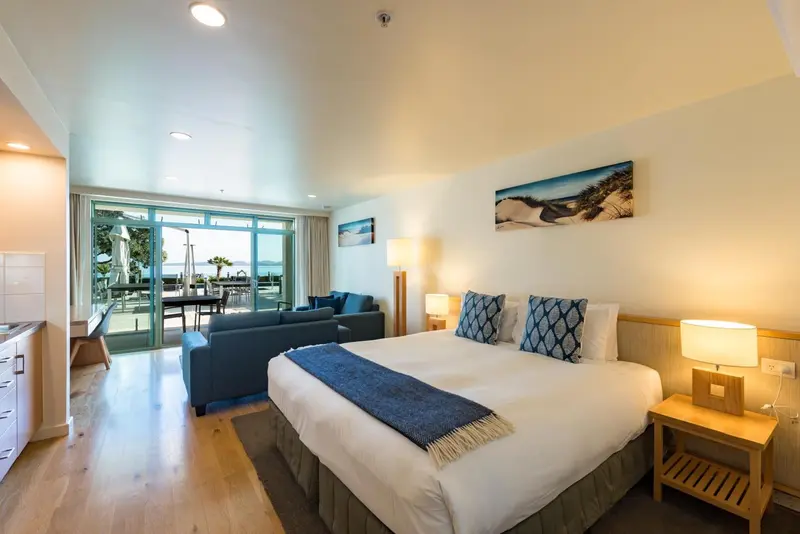 Une chambre lumineuse avec un grand lit et un coin salon donnant sur une terrasse.