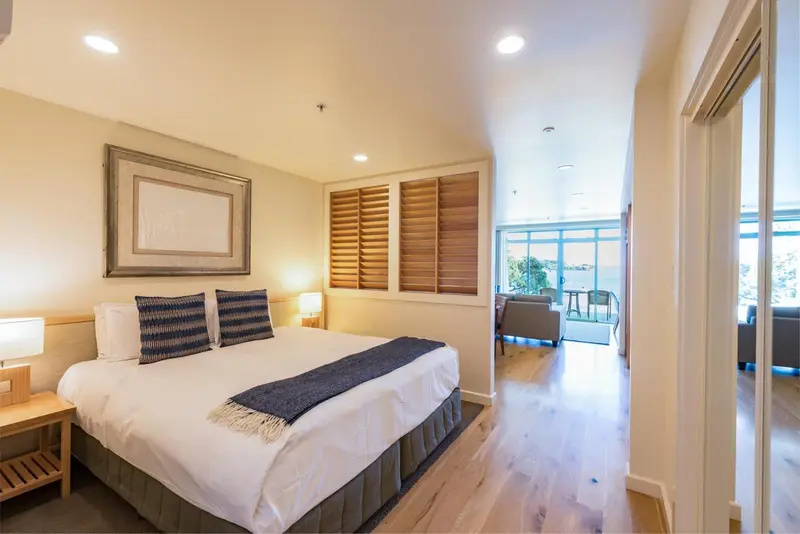 Une chambre lumineuse avec un grand lit et un accès à un espace salon.