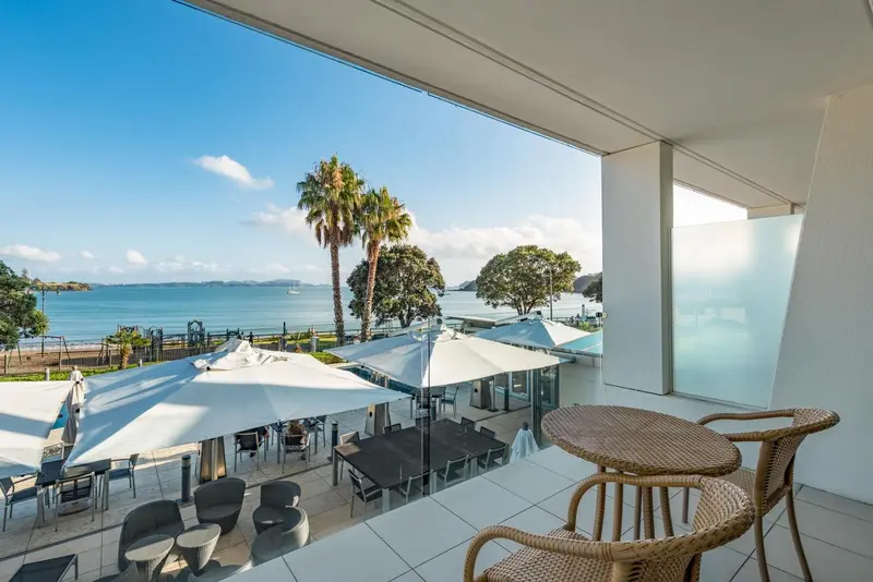 Terrasse avec mobilier en osier donnant sur une vue mer et une plage.