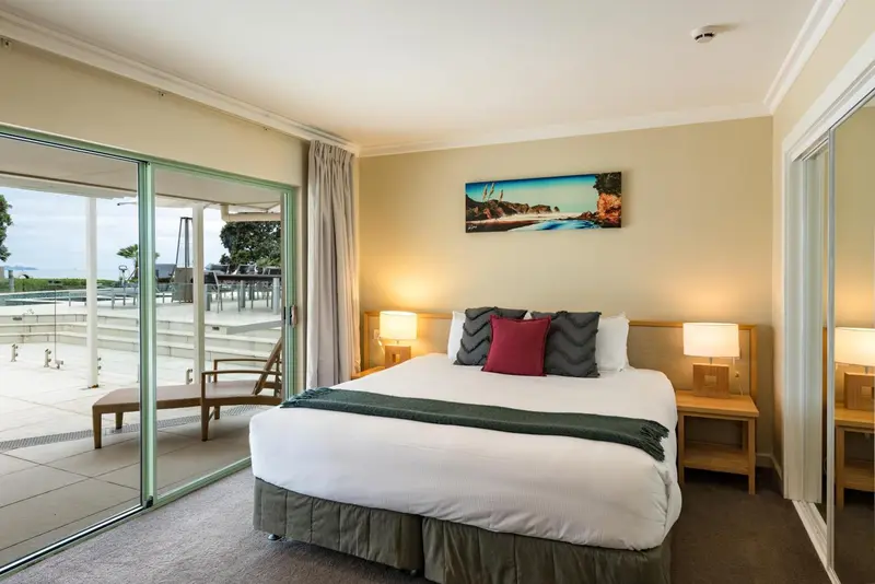Une chambre lumineuse avec un grand lit et un accès à une terrasse avec vue sur la piscine.