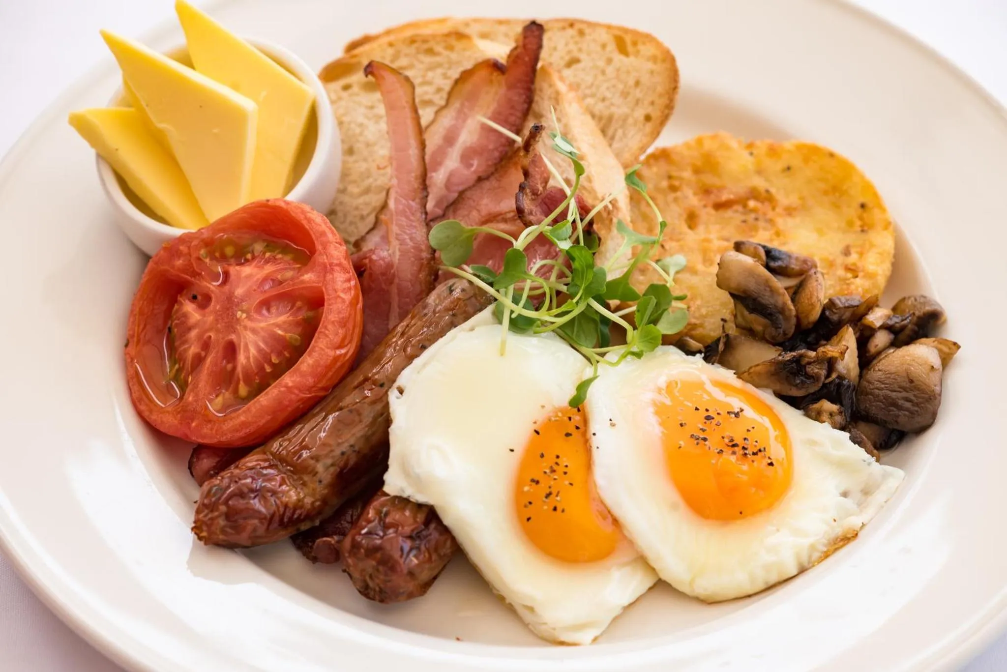 Assiette copieuse avec œufs, bacon, saucisses, champignons et garnitures.