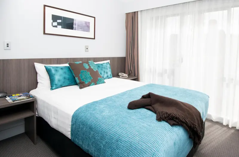 Une chambre lumineuse avec un grand lit recouvert d'une courtepointe bleue et turquoise.