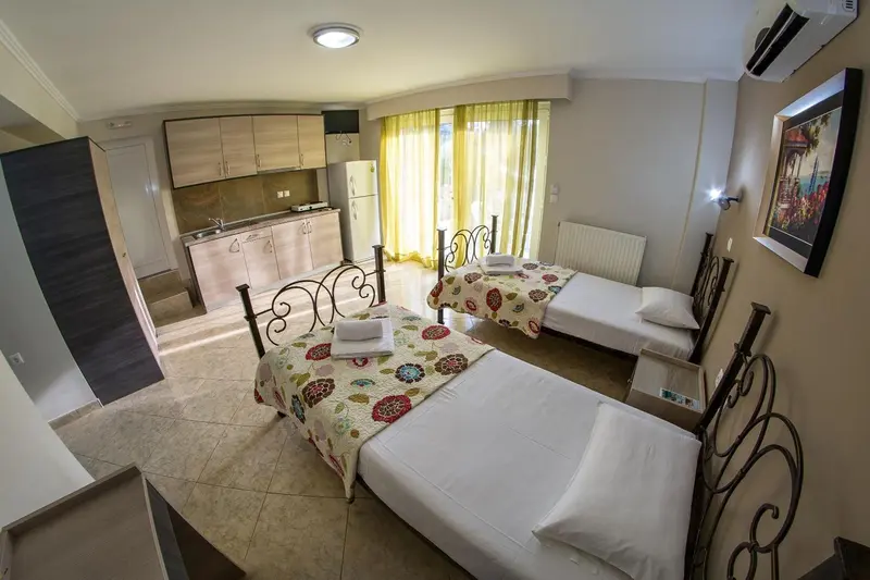 Une chambre lumineuse avec deux lits et un coin cuisine.