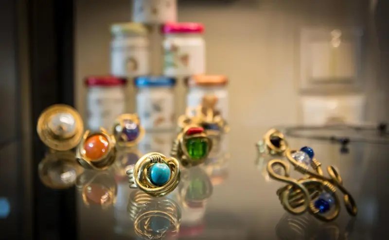 Bijoux dorés et colorés exposés sur un comptoir vitré.