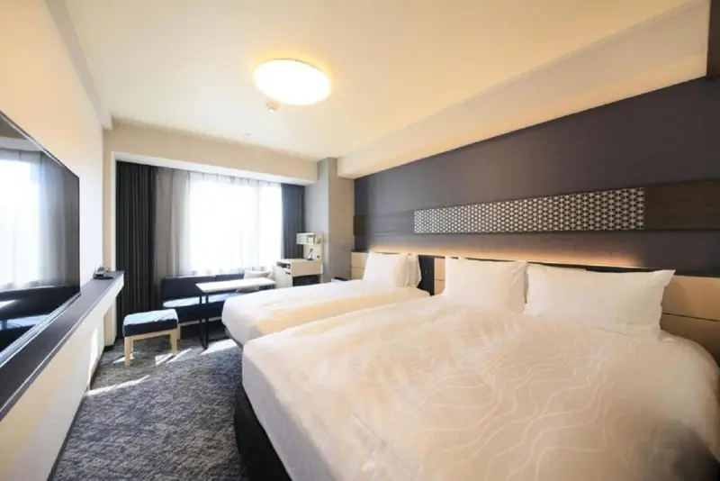 Chambre d'hôtel moderne avec deux lits simples et une fenêtre.