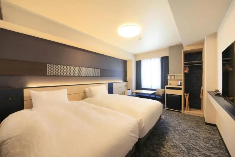Une chambre d'hôtel lumineuse avec deux lits simples et un espace détente.