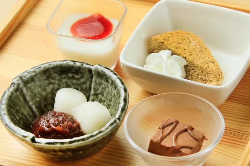 Assortiment de mets japonais présentés dans des récipients variés sur un plateau en bois.