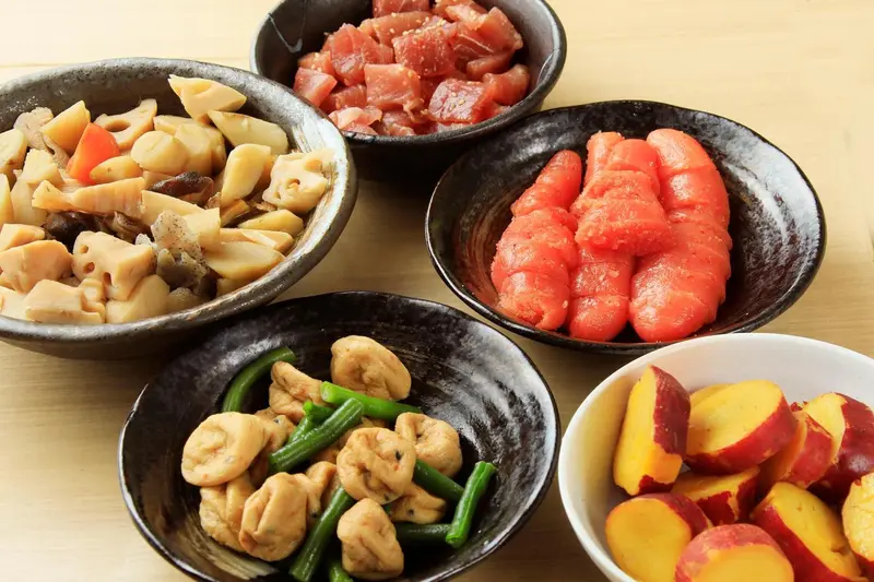 Assortiment de plats japonais colorés servis dans des bols noirs.