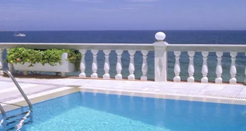 Terrasse blanche avec balustrade et vue sur la mer.