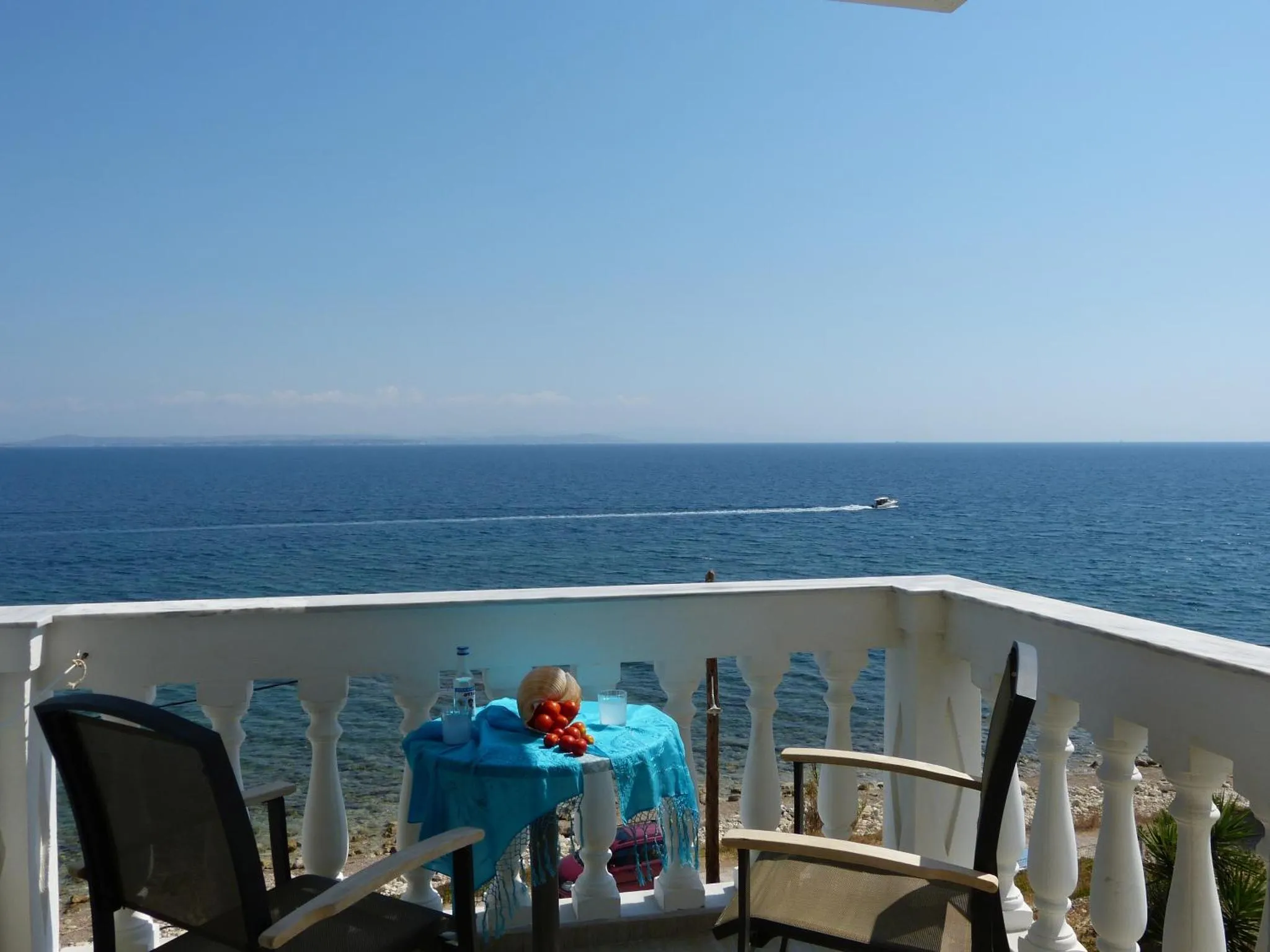 Une table et des chaises sont disposées sur une terrasse avec vue sur la mer.