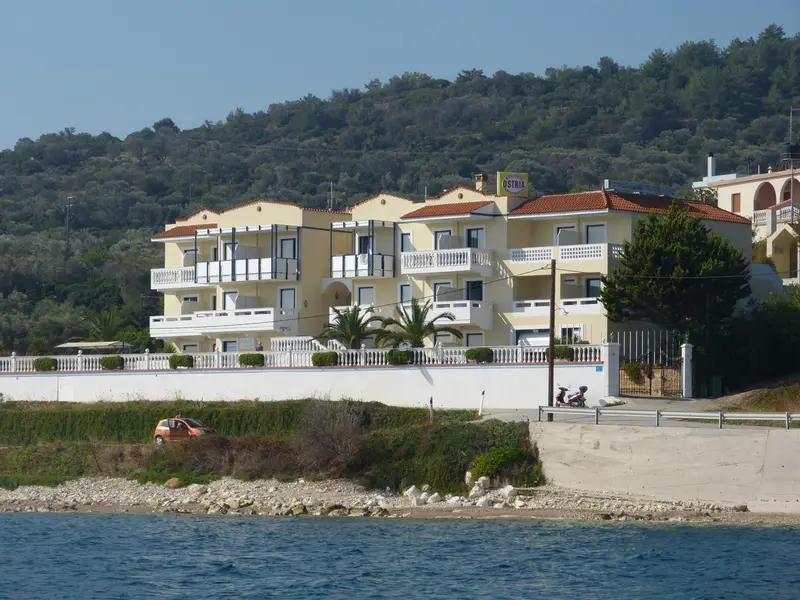 Bâtiment jaune à plusieurs étages avec des balcons et une vue sur la mer.