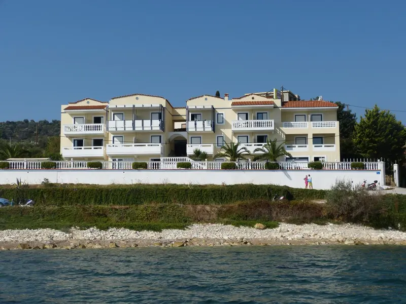Bâtiment jaune à balcons blancs surplombant une côte rocheuse.