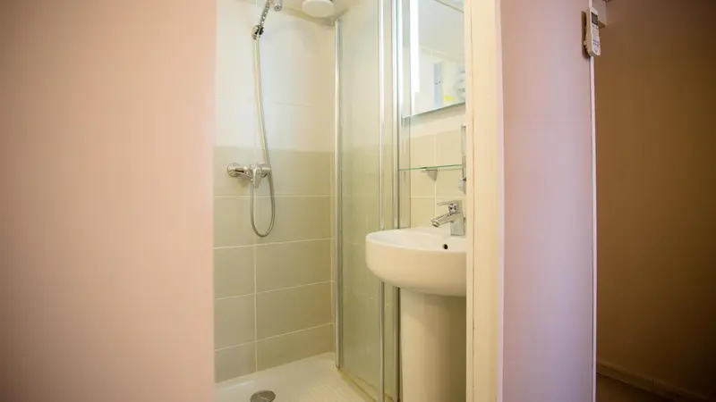 Une douche à l'italienne avec un robinet et un miroir.