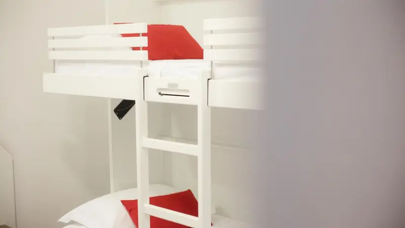 Lits superposés blancs avec oreillers rouges dans une chambre.