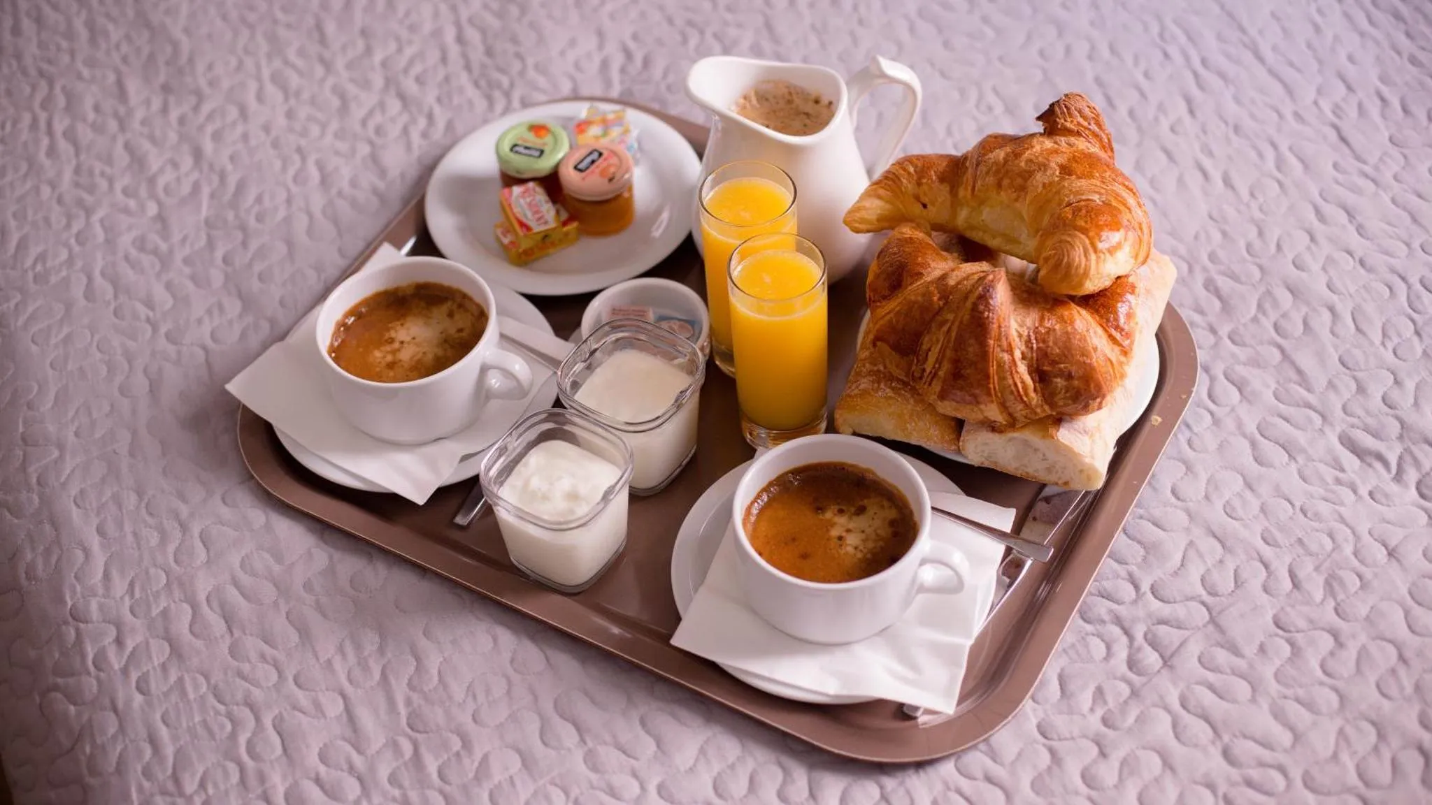 Un plateau de petit-déjeuner avec des viennoiseries, des jus de fruits et des boissons chaudes.