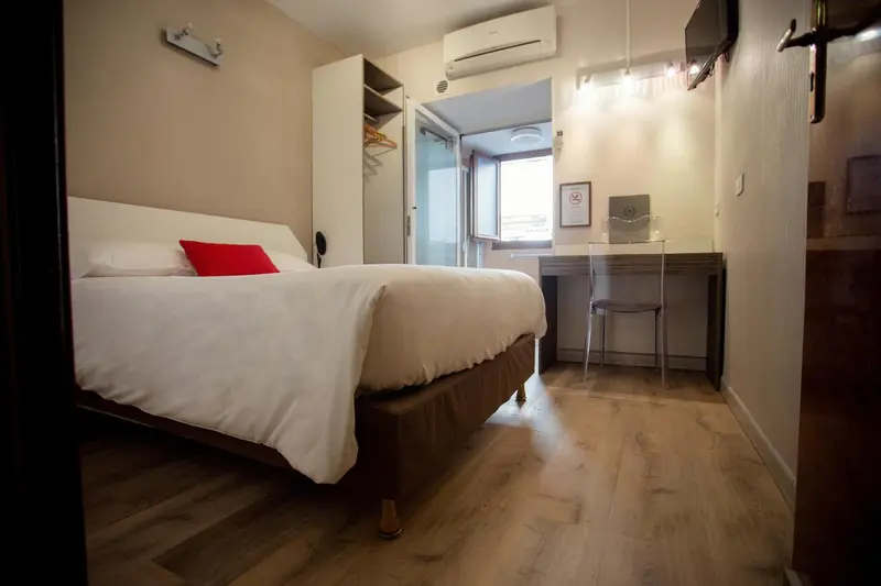 Une chambre lumineuse avec un lit simple et un bureau près d'une fenêtre.