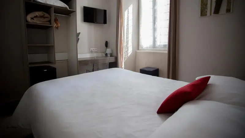 Une chambre lumineuse avec un lit simple et un bureau près de la fenêtre.