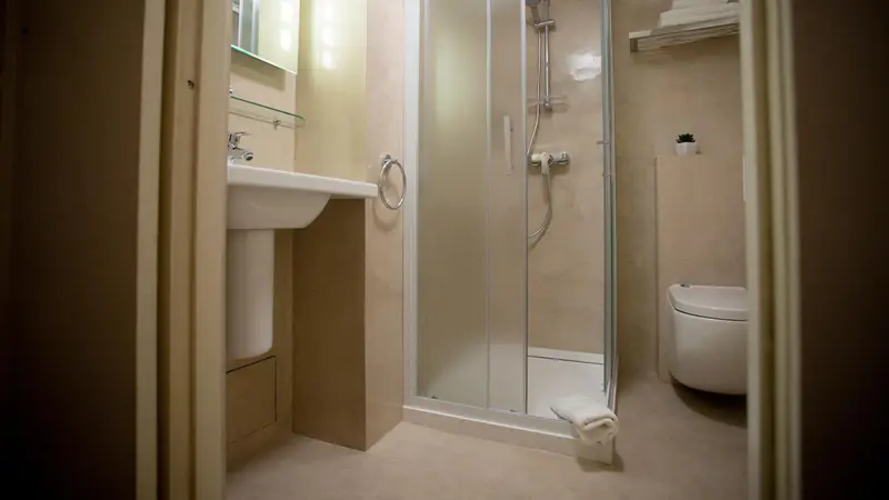 Une salle de bain claire avec douche et lavabo.