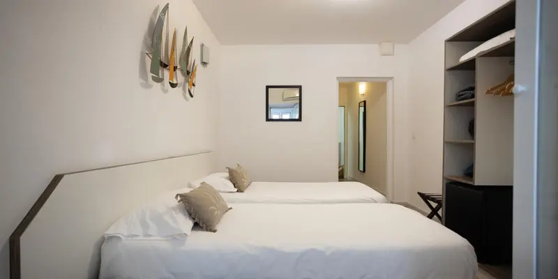 Une chambre lumineuse avec deux lits simples et une décoration murale.