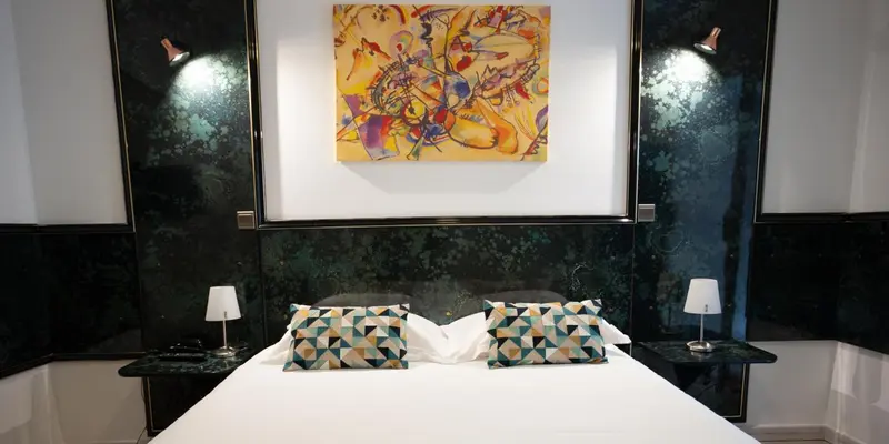 Une chambre avec un grand lit recouvert d'une courtepointe blanche et de coussins décoratifs.