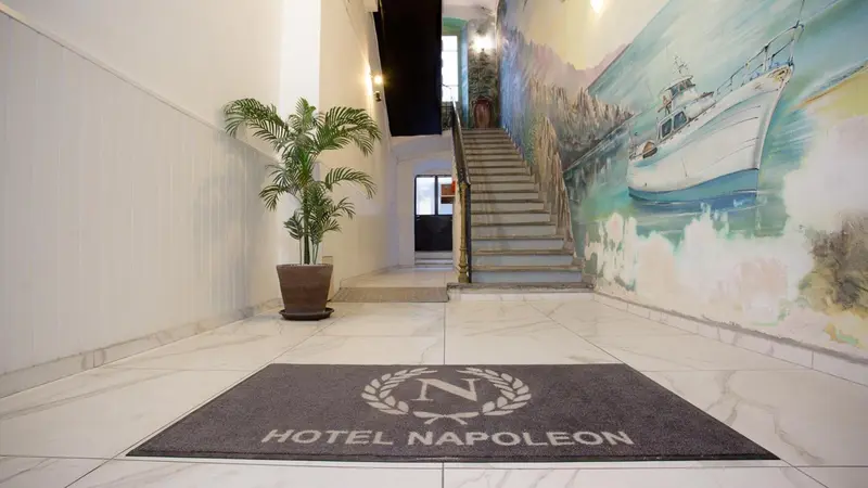 Hall d'entrée lumineux avec un escalier et une peinture murale représentant des bateaux.