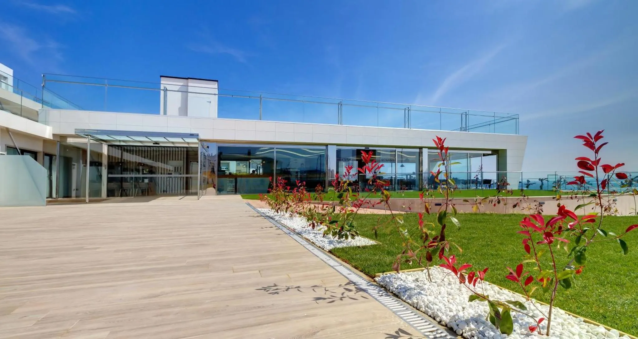 Terrasse moderne avec vue sur la mer et végétation soignée.
