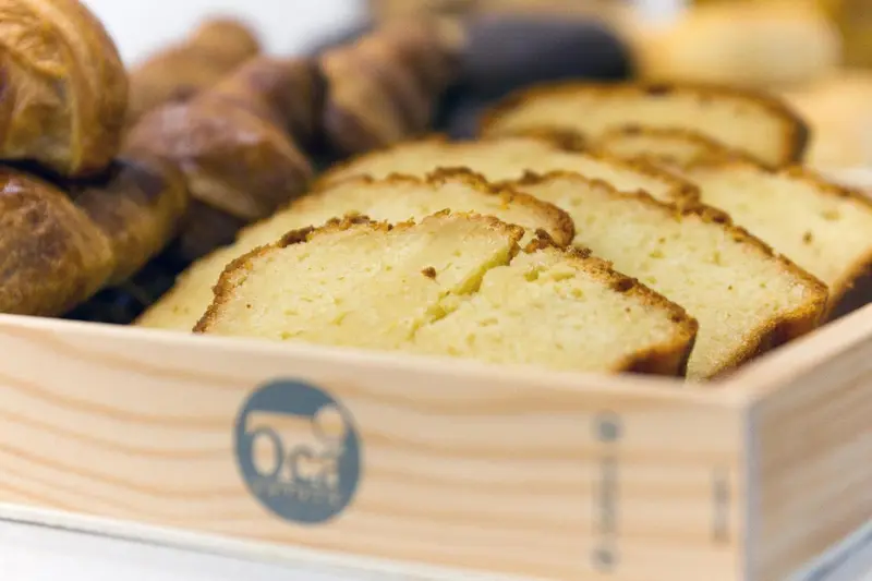 Assortiment de viennoiseries et de pain tranché présentés dans un panier en bois.