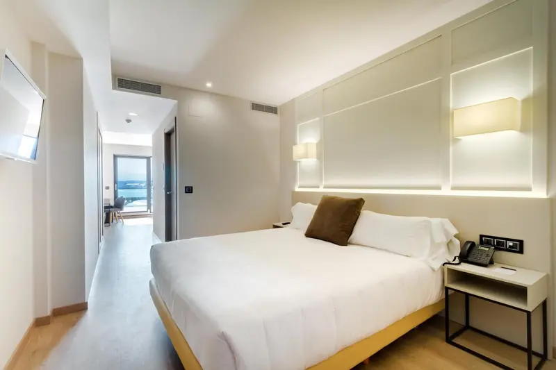Chambre lumineuse avec un grand lit et une décoration moderne.