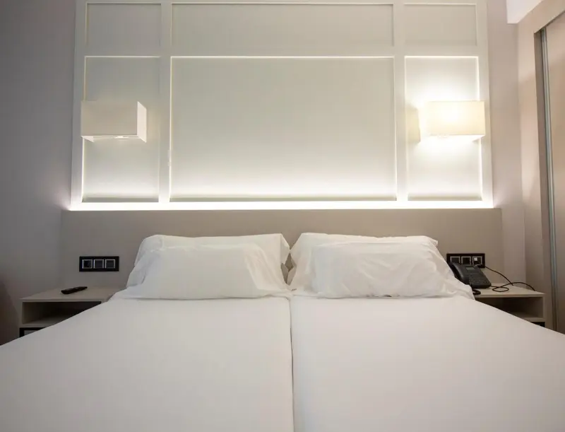 Un lit double avec des oreillers blancs dans une chambre lumineuse.