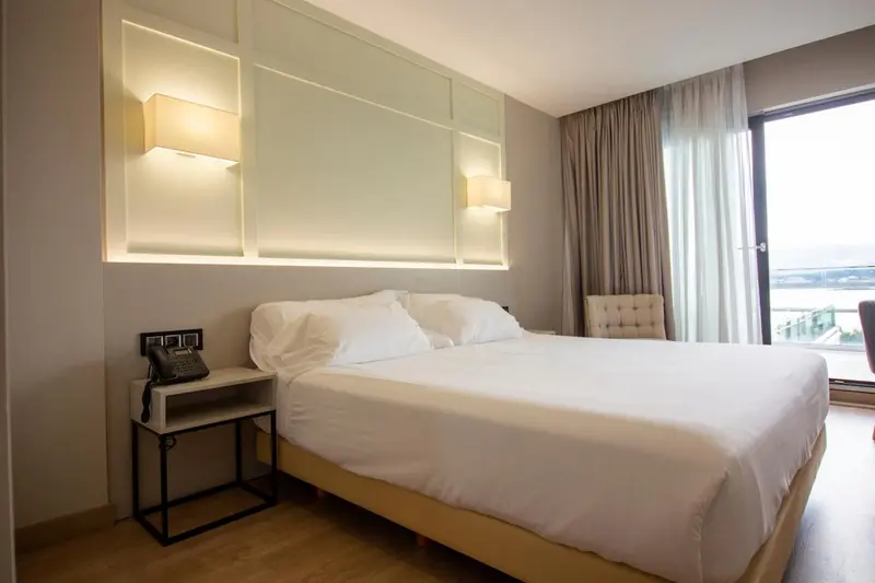 Une chambre lumineuse avec un grand lit et une fenêtre.